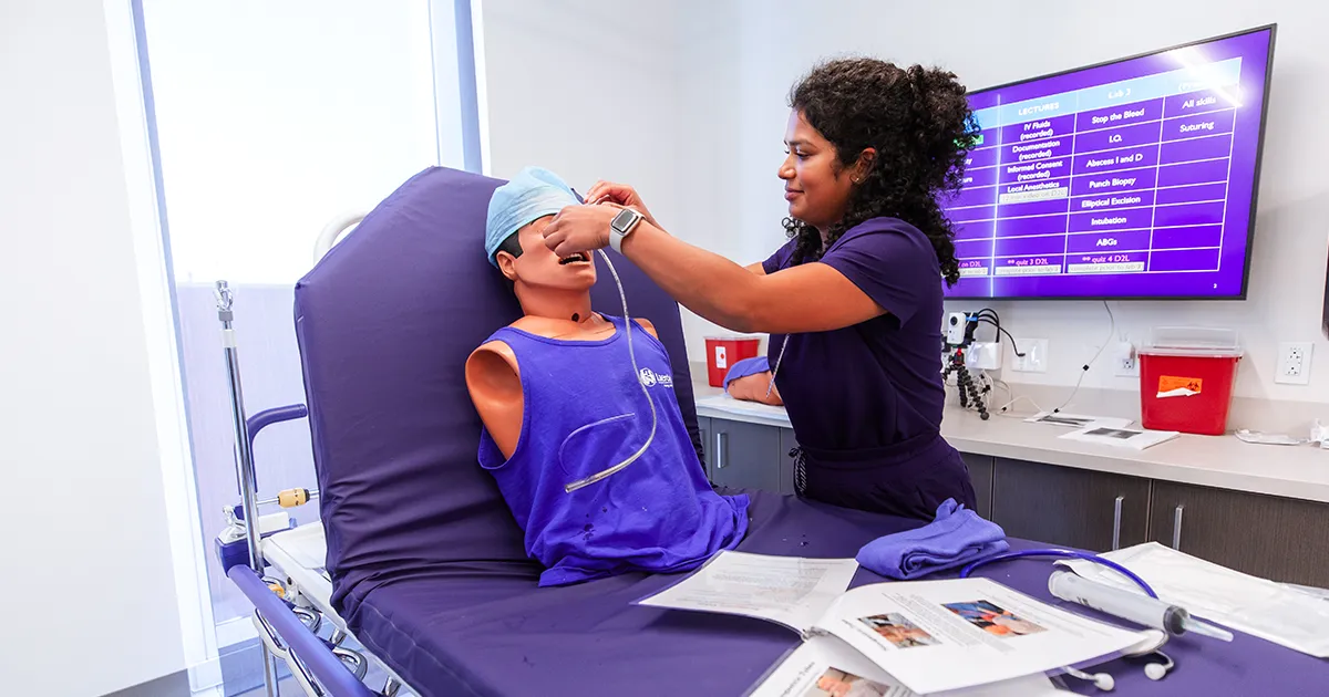 A DMU student practices inserting a nasal tube in the Adams Task Training Lab.