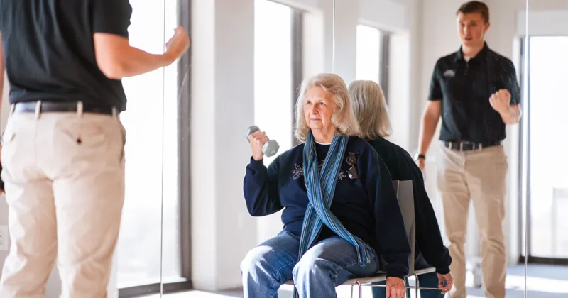 A DMU student leads a patient in a resistance exercise at the annual 50 and Better Health Fair.