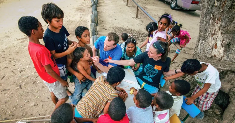 Two DMU students administer oral vaccines to children in a developing country.