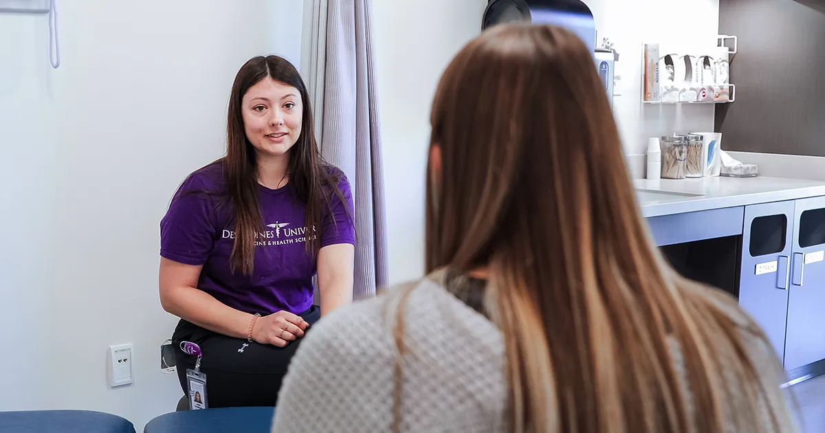 DMU student practicing patient interaction in a clinical exam room within the simulation center.