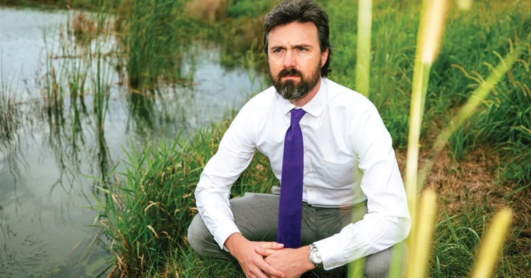 Jason Semprini, PhD, MPP, sitting near the pond on DMU’s campus.