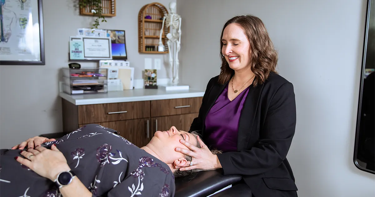 Kirsten Radke, PT, DPT’15, performs a craniosacral therapy technique with a patient lying on a treatment table in a physical therapy clinic.