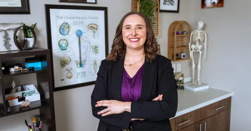 Kirsten Radke, PT, DPT’15, stands in her clinic in front of anatomy and craniosacral system displays.