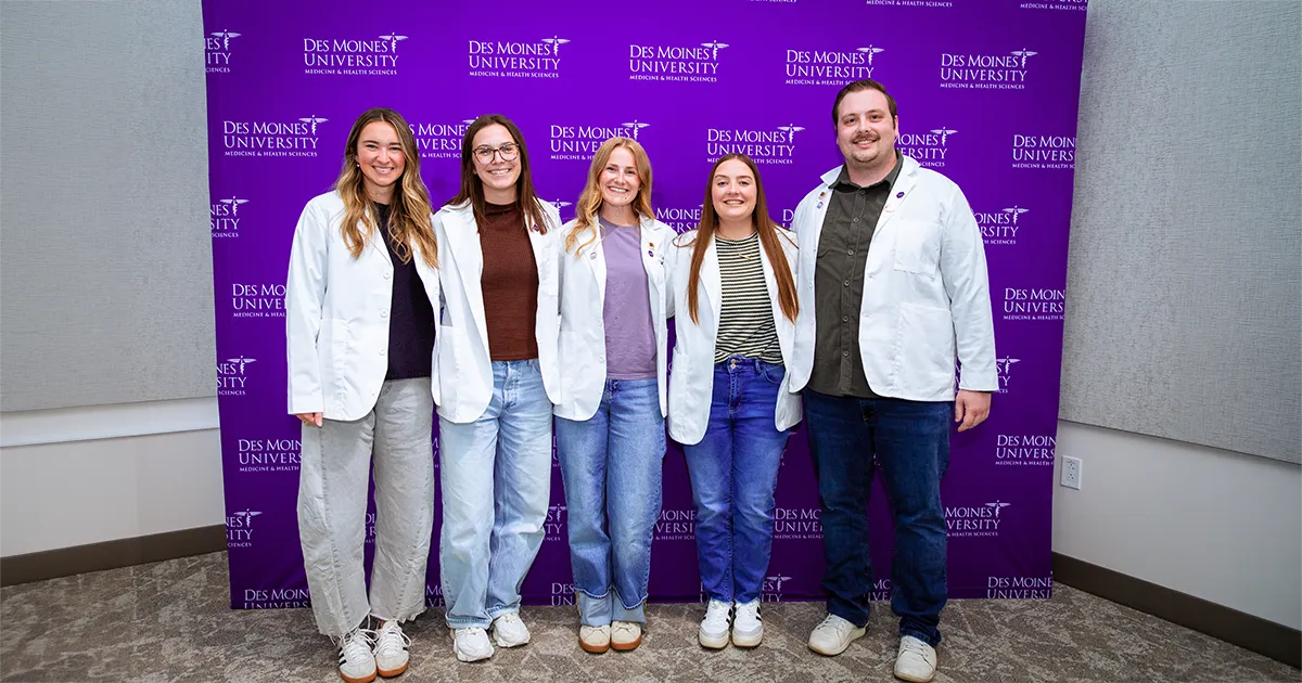 Group of five DMU students pose for a photo in front of a purple Des Moines University Medicine and Health Sciences backdrop during the annual Leadership and Service Awards ceremony.