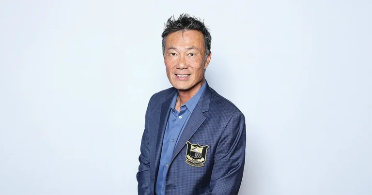 Benjamin Lam, DO’92, seated in a blue blazer with an embroidered crest, looking toward the camera in a professional studio portrait.