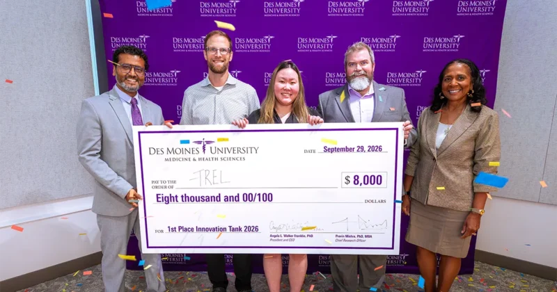 Members of the winning Innovation Tank team hold a ceremonial $8,000 first-place prize check during the 2026 competition as confetti falls around them.