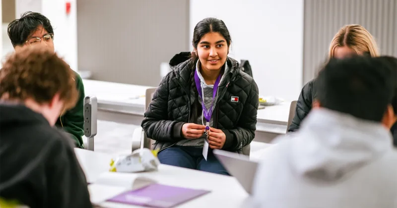 High school students participate in a small-group discussion during DMU’s Mini Medical School program, seated around classroom tables.