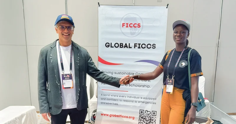 Parag Patel, DO’92, stands with a Global FICCS volunteer, holding hands in front of a Global FICCS display at an event focused on health care education and training.