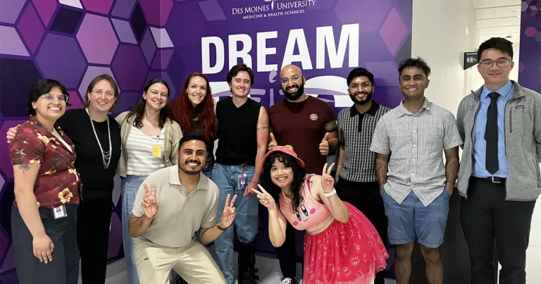 Group of DMU students standing on a stage in front of a purple backdrop during the Iowa Storytellers Project.