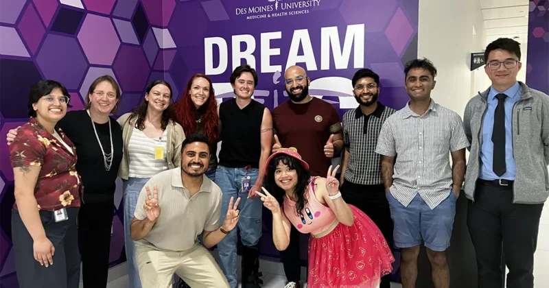Group of DMU students standing on a stage in front of a purple backdrop during the Iowa Storytellers Project.