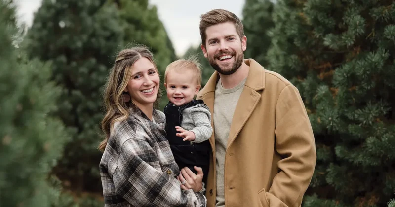 Makenzie Driscoll, MSPAS’21, poses outdoors with her husband, Logan Driscoll, MSPAS’21, and their young child among evergreen trees. The family stands together in coordinated fall clothing in a natural setting.